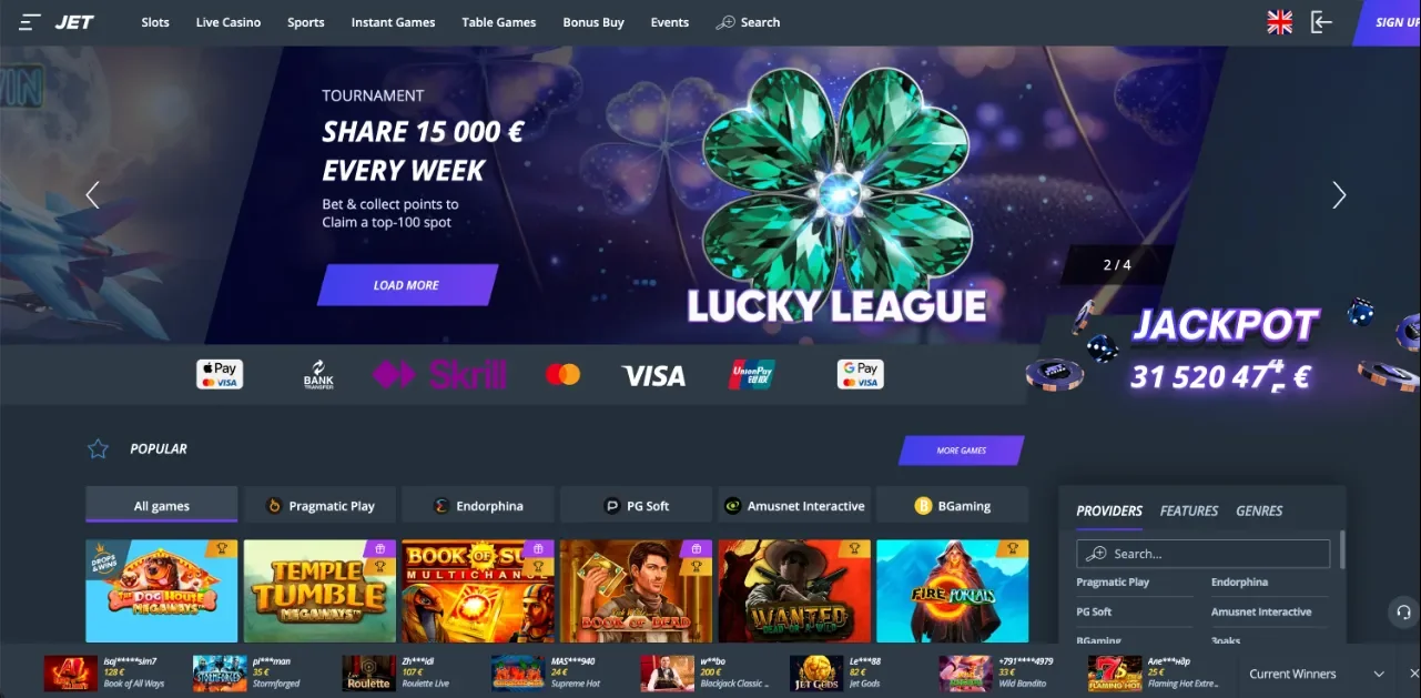 Jet Casino kezdőképernyő — Lucky League 15 000 € heti torna bannere „Bet & collect points” szöveggel, smaragd lóhere grafika, Load More gomb, JACKPOT számláló euróban, Providers / Features / Genres szűrőoszlop, fizetési logók, populáris nyerőgépek rácsa és Current Winners kártyasáv — lila-kék sötét téma (szerkesztőségi képernyőkép a teljes Jet értékeléshez).